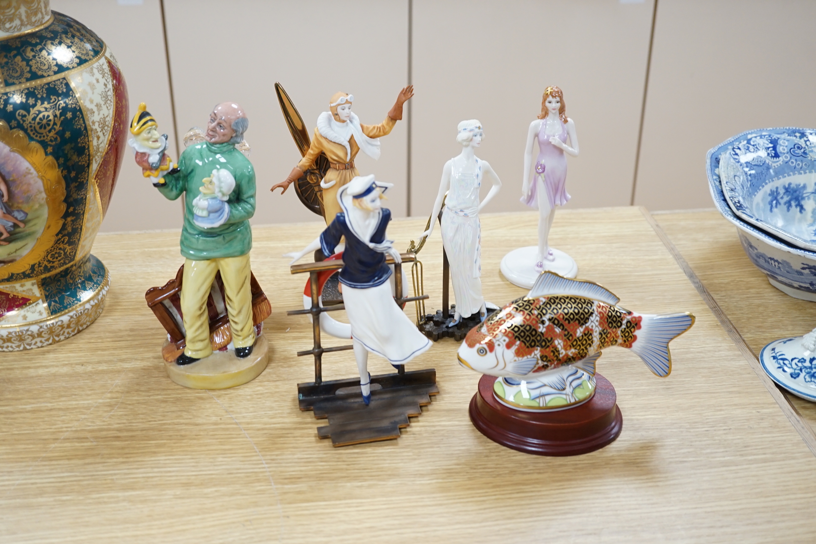 Four Royal Doulton character figures, a Royal Crown Derby Koi Carp paper weight, a continental putti group, a Coalport figure, a glass model of a golfer and three mixed metal and ceramic figures (11)